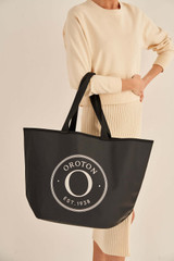 Profile view of model wearing the Oroton Kaia Shopper Tote in Black and Coated canvas material for Women .