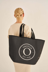 Profile view of model wearing the Oroton Kaia Shopper Tote in Black and Coated canvas material for Women .