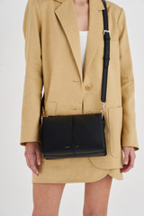 Profile view of model wearing the Oroton Emma Small Day Bag in Black and Pebble Leather for Women .