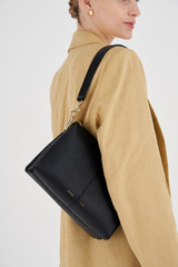 Profile view of model wearing the Oroton Emma Small Day Bag in Black and Pebble Leather for Women .