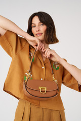 Profile view of model wearing the Oroton Colt Small Baguette in Brandy and Smooth leather for Women .