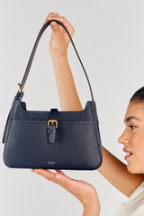 Profile view of model wearing the Oroton Dylan Baguette in Dark Navy and Pebble Leather for Women .