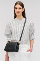 Profile view of model wearing the Oroton Alice Crossbody in Black and Premium pebbled leather exterior for Women .