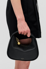 Profile view of model wearing the Oroton Clara Mini Bag in Black and Pebble leather for Women .
