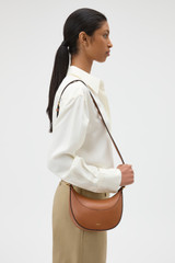 Profile view of model wearing the Oroton Florence Small Shoulder Bag in Cognac and Premium smooth leather for Women .