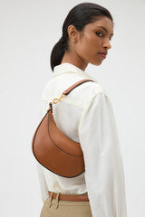 Profile view of model wearing the Oroton Florence Small Shoulder Bag in Cognac and Premium smooth leather for Women .