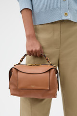 Profile view of model wearing the Oroton Mica Bowler in Brandy and Premium pebble grain leather for Women .
