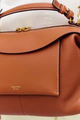 Profile view of model wearing the Oroton Mica Bowler in Brandy and Premium pebble grain leather for Women .