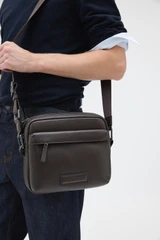 Profile view of model wearing the Oroton Ethan Pebble A5 Zip Crossbody in Bitter Chocolate and Premium pebble leather for Men .