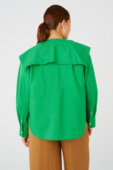 Profile view of model wearing the Oroton Cape Blouse in Jewel Green and 100% cotton for Women