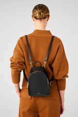 Profile view of model wearing the Oroton Inez Mini Backpack in Black and Premium saffiano leather for Women .