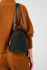 Profile view of model wearing the Oroton Inez Mini Backpack in Black and Premium saffiano leather for Women .