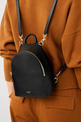 Profile view of model wearing the Oroton Inez Mini Backpack in Black and Premium saffiano leather for Women .