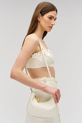 Profile view of model wearing the Oroton Clara Mini Bag in Paper White and Pebble leather for Women .