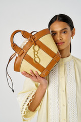 Profile view of model wearing the Oroton Harper Small Tote in Natural/Brandy and Woven straw with smooth leather trims for Women