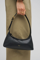Profile view of model wearing the Oroton Cinder Mini Baguette in Black and Smooth leather for Women .