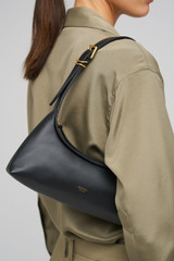Profile view of model wearing the Oroton Cinder Mini Baguette in Black and Smooth leather for Women .