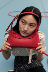 Profile view of model wearing the Oroton CINDER MINI BAGUETTE in Dark Poppy and Smooth leather for Women .