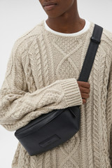 Profile view of model wearing the Oroton Ethan Pebble Belt Bag in Black and Pebble Leather for Men .