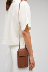 Profile view of model wearing the Oroton Margot Phone Crossbody in Whiskey and Premium pebble leather for Women .