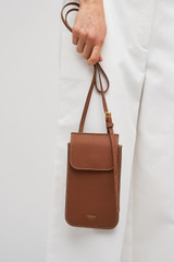 Profile view of model wearing the Oroton Margot Phone Crossbody in Whiskey and Premium pebble leather for Women .