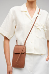 Profile view of model wearing the Oroton Margot Phone Crossbody in Whiskey and Premium pebble leather for Women .