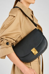 Profile view of model wearing the Oroton Yvonne Medium Day Bag in Black and Pebble Leather for Women .
