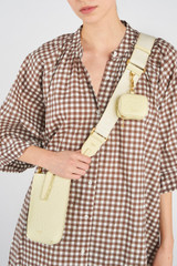 Profile view of model wearing the Oroton Fife Webbing Strap in Lemon Butter and Poly Jacquard webbing for Women .