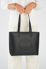 Profile view of model wearing the Oroton Polly Medium Zip Tote in Black and Premium pebble leather for Women .