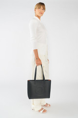 Profile view of model wearing the Oroton Polly Medium Zip Tote in Black and Premium pebble leather for Women .