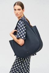 Profile view of model wearing the Oroton Emilia Large Tote in North Sea and Pebble leather for Women .