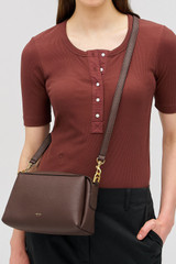 Profile view of model wearing the Oroton Alice Crossbody in Bear Brown and Premium pebbled leather exterior for Women .