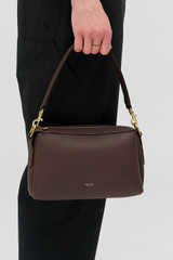 Profile view of model wearing the Oroton Alice Crossbody in Bear Brown and Premium pebbled leather exterior for Women .