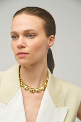 Profile view of model wearing the Oroton Tulip Necklace in Gold and Brass for Women .