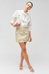 Profile view of model wearing the Oroton Flower Sequin Mini Skirt in Limestone and 100% linen for Women