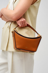 Profile view of model wearing the Oroton Fable Small Day Bag in Amber and Smooth leather for Women