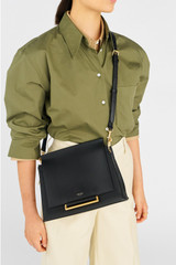 Profile view of model wearing the Oroton Elm Medium Satchel in Black and Premium smooth pebble leather for Women .
