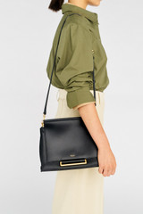 Profile view of model wearing the Oroton Elm Medium Satchel in Black and Premium smooth pebble leather for Women .