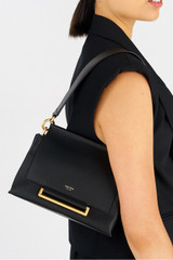 Profile view of model wearing the Oroton Elm Small Satchel in Black and Premium smooth pebble leather for Women .