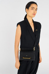 Profile view of model wearing the Oroton Elm Small Satchel in Black and Premium smooth pebble leather for Women .