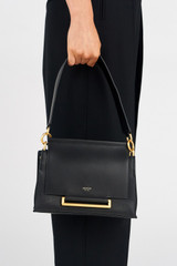 Profile view of model wearing the Oroton Elm Small Satchel in Black and Premium smooth pebble leather for Women .