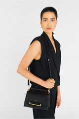 Profile view of model wearing the Oroton Elm Small Satchel in Black and Premium smooth pebble leather for Women .