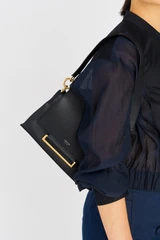 Profile view of model wearing the Oroton Elm Small Satchel Bag in Navy and Smooth Pebble Leather for Women .