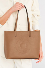 Profile view of model wearing the Oroton Polly Medium Zip Tote in Tan and Premium pebble leather for Women .