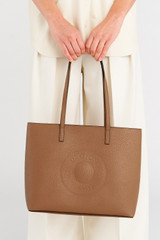 Profile view of model wearing the Oroton Polly Medium Zip Tote in Tan and Premium pebble leather for Women .