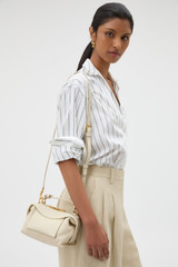 Profile view of model wearing the Oroton Mica Mini Bowler in Cashew and Pebble leather for Women .