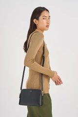 Profile view of model wearing the Oroton Iris Double Zip Crossbody in Black/Black and Premium pebble leather  for Women .