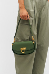 Profile view of model wearing the Oroton Colt Small Baguette in Moss and Smooth leather for Women