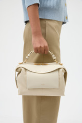 Profile view of model wearing the Oroton Mica Bowler in Cashew and Embossed leather with smooth leather trims for Women .