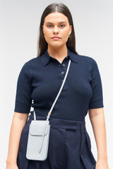 Profile view of model wearing the Oroton Margot Phone Crossbody in Dusk Blue and Pebble leather for Women .